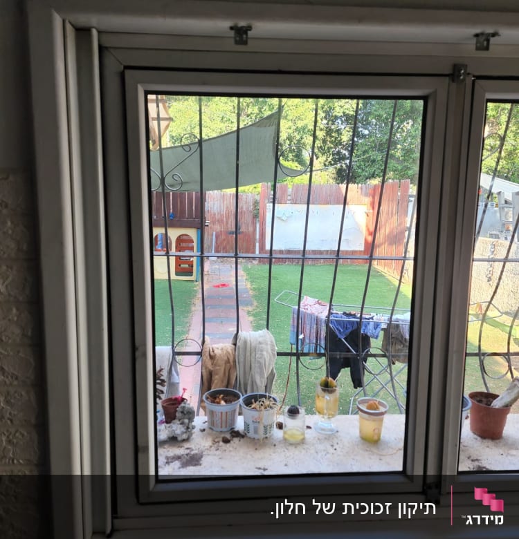 חלון זכוכית עם אדן מלא בעציצים וכוסות